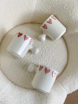 كوب أبيض قلوب مع يد غريبة