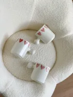 كوب أبيض قلوب مع يد غريبة
