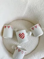 كوب أبيض قلوب مع يد غريبة