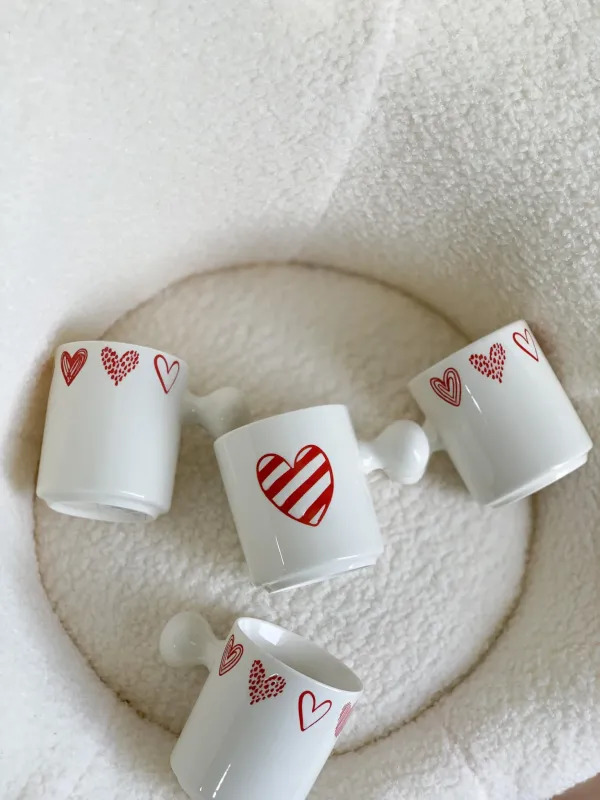 كوب أبيض قلوب مع يد غريبة