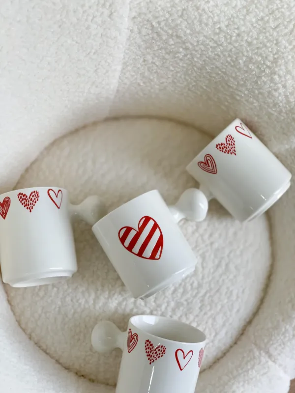 كوب أبيض قلوب مع يد غريبة